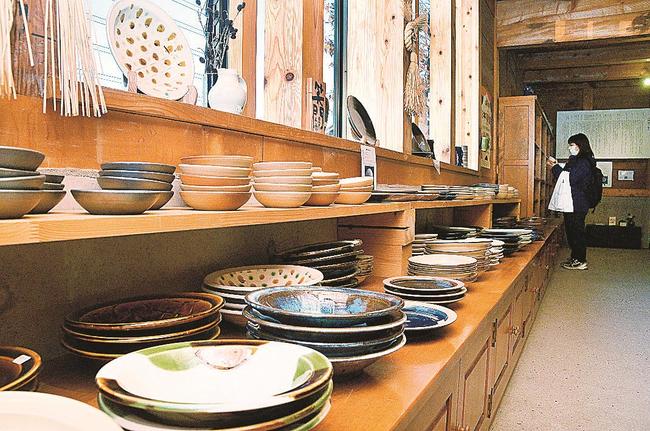 無自性館内で販売される出西窯の器を品定めする来店客＝出雲市斐川町出西