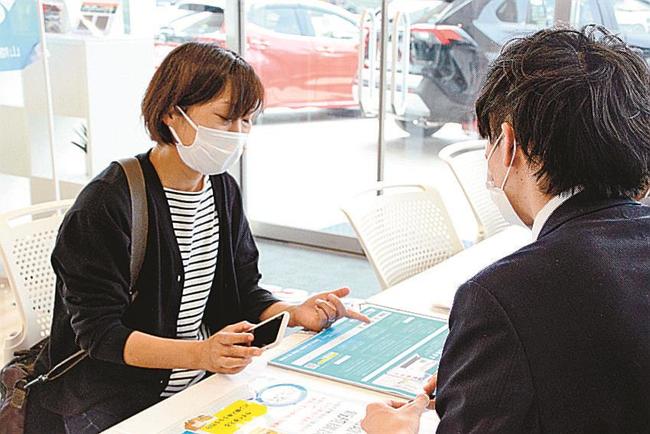 Ｓデジについて説明を受ける来店者（左）＝松江市西津田、ネッツトヨタ島根松江店