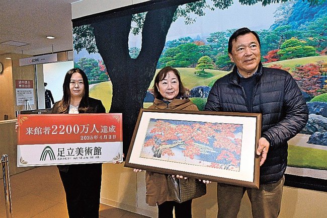 ２２００万人目の来場者となった坂本隆盛さん（右）＝安来市古川町、足立美術館