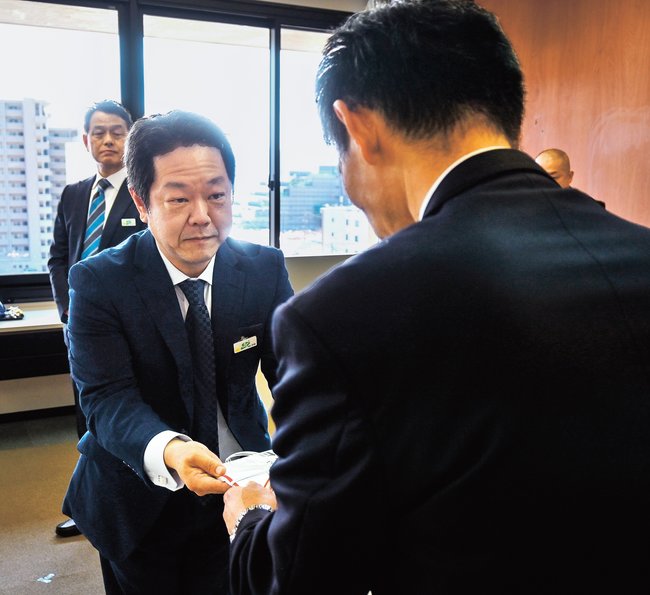 丸山直紀本部長（右）に目録を手渡す宇畑学取締役ビジネスプロデュース局長＝松江市殿町、島根県警本部