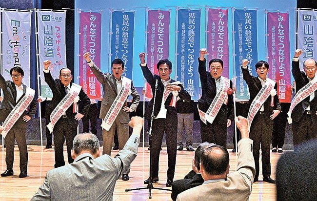 頑張ろうコールで拳を突き上げる沿線自治体の首長ら＝浜田市野原町、島根県立大浜田キャンパス