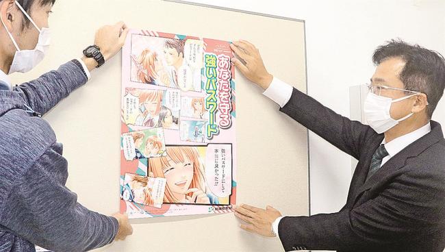 ポスターを掲示する窪田浩仁課長(右)。生徒の目に止まるよう漫画調にしている=松江市浜乃木8丁目、湖南中学校