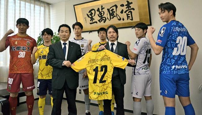 新しいユニホームを披露するＦＣ神楽しまねの選手と実信憲明監督（右から３人目）、大屋剛専務取締役（左から３人目）＝松江市殿町、山陰中央新報社