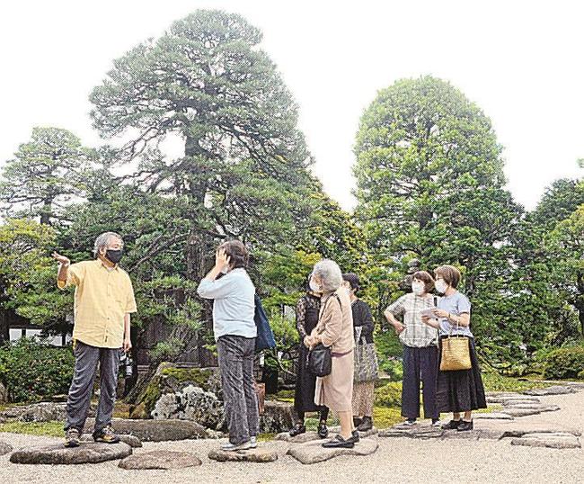 宇野真一さん（左）から出雲流庭園の特徴を聞く参加者＝出雲市浜町、出雲文化伝承館
