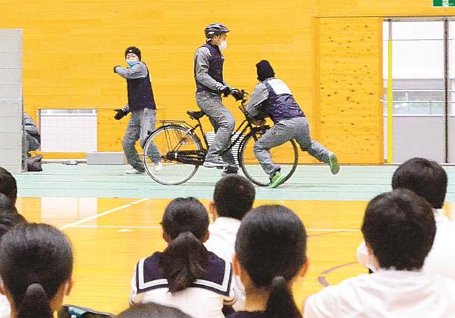 自転車と歩行者の事故場面を再現するスタントマン＝大田市大田町、大田第一中学校