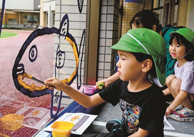 真剣な表情でガラスに描かれた絵に色を塗る園児＝鳥取県日南町霞、町総合文化センター