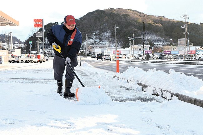 店周辺の除雪作業をする国道５４号沿いのガソリンスタンドの従業員＝５日午前７時５０分、雲南市木次町里方