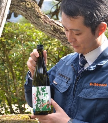 ウマ娘とコラボした限定酒を手にする田村浩一郎専務＝島根県奥出雲町横田、簸上清酒