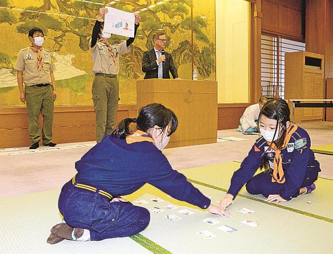 マクミランさん（奥左から３人目）が読み上げた札に反応する児童＝出雲市大社町杵築東、出雲大社