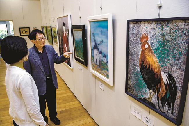 来館者に作品を説明する小村俊美理事長（右）＝出雲市浜町、出雲文化伝承館縁結び交流館