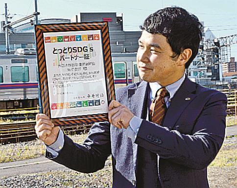 パートナー証を手に今後の活動への意欲を高める松原啓執行委員長＝米子市内