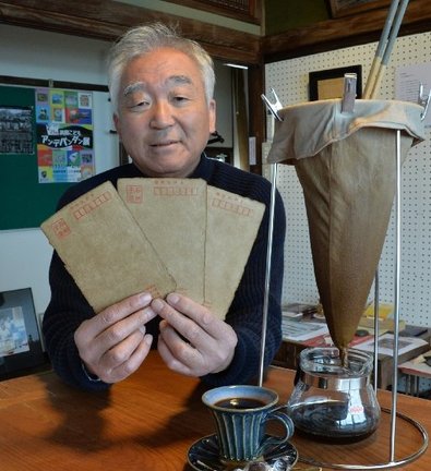 ヨシタケコーヒーで染色したポストカードを手にする田中昭則さん=浜田市西村町、Gallery&Cafe FUN