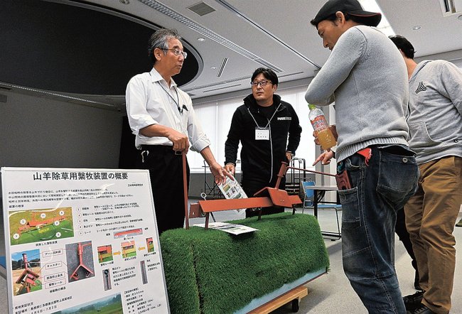ヤギが除草する際の装置について話す青戸貞夫さん（左端）と参加者＝出雲市今市町、出雲科学館