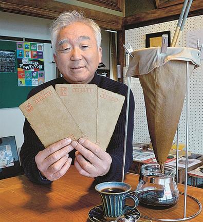 ヨシタケコーヒーで染色したポストカードを手にする田中昭則さん＝浜田市西村町、Ｇａｌｌｅｒｙ＆Ｃａｆｅ　ＦＵＮ