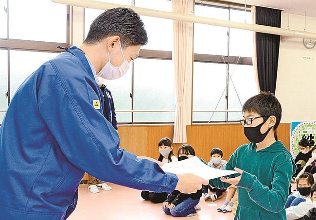 出雲村田製作所の社員（左）から賞状を受け取る児童＝出雲市斐川町富村、西野小学校