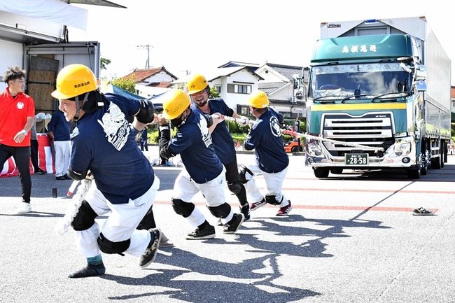 綱を手に懸命にトラックを引っ張る参加者＝江津市江津町、市総合市民センター駐車場