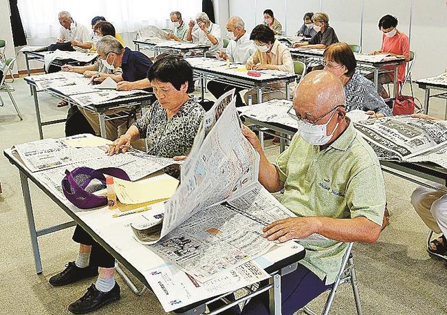 新聞をめくってクイズの答えを探す参加者