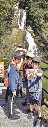 滝を背景に記念写真を撮る子どもたち＝江津市波積町、岩瀧寺の滝