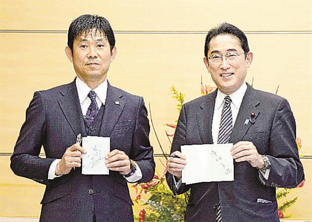 Ｗ杯日本代表メンバーと面会し、森保一監督（左）と互いにサインした手帳を交換して笑顔の岸田文雄首相＝１２月８日、首相官邸