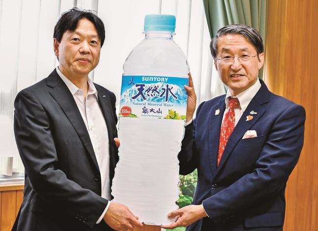 平井伸治知事に目録の天然水ボードを手渡す栗原俊明工場長（左）＝米子市糀町１丁目、鳥取県西部総合事務所