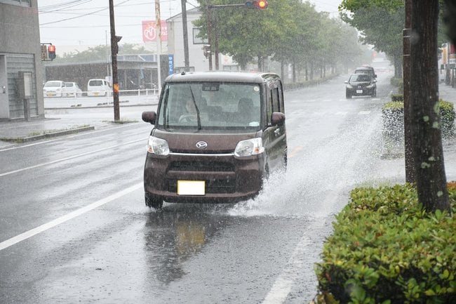水しぶきを上げながら走行する自動車＝出雲市駅南１丁目