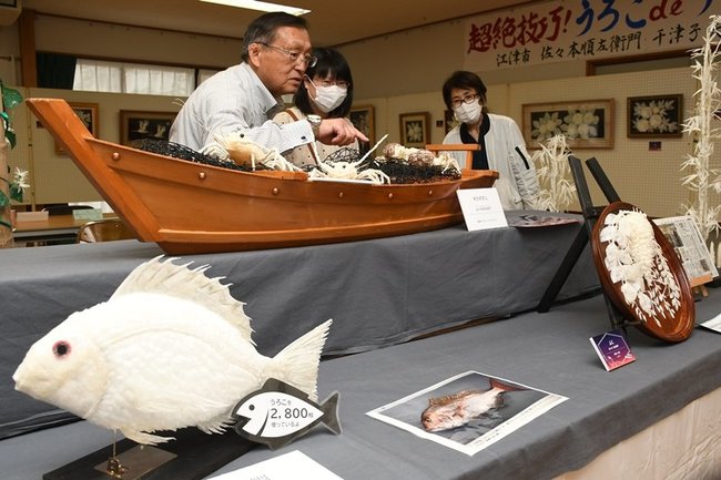 うろこで作られた作品に見入る来場者＝出雲市多伎町口田儀、多伎文化伝習館