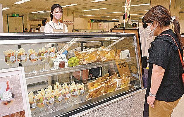 二十世紀梨やイチジクのスイーツを眺める来場者（右）＝米子市西福原２丁目、米子しんまち天満屋
