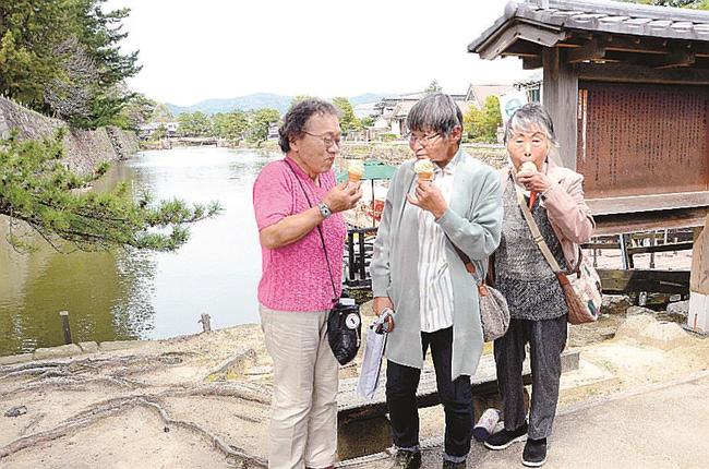 松江城周辺を散策し、アイスクリームを食べる観光客=松江市殿町