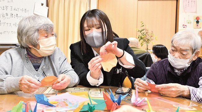 お年寄りに折り紙を手ほどきする生徒(中央)=江津市和木町、よろこぼう屋デイサービスの家