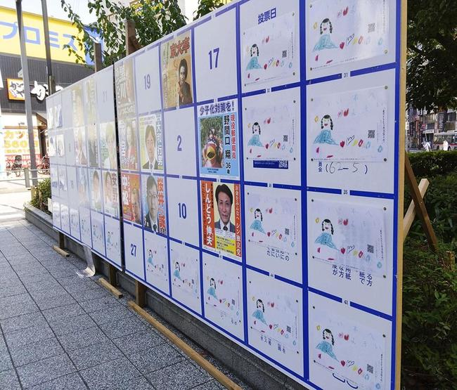 ＪＲ蒲田駅近くの掲示板に張られた、女の子や花の絵と共にＱＲコードが掲載された東京都知事選のポスター（左右と下）＝４日