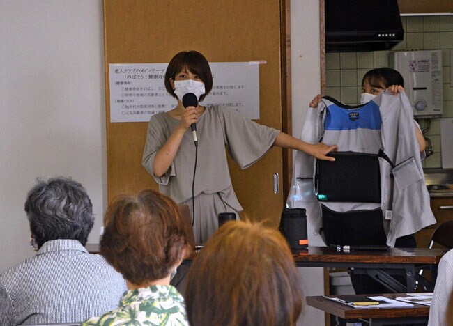 エアマットが入るベスト内側のポケットを紹介する芹川由布子助教（中央）＝松江市黒田町、黒田集会所