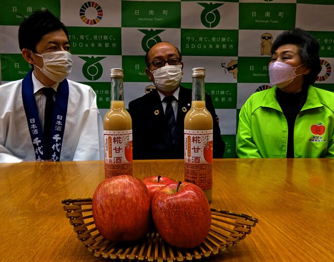 阿毘縁高原リンゴを使って商品化した糀甘酒を前に、談笑する関係者＝鳥取県日南町霞、町役場