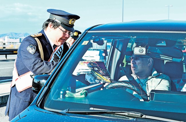 チラシを渡し飲酒運転や詐欺への注意を呼びかける山内剛店長（左）＝松江市袖師町、とるぱ駐車場