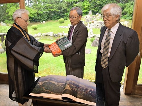 神一紀道住職（左）に「近代日本夜明けの道を歩く」を寄贈する吉﨑佳慶さんと矢冨巌夫さん（右）＝益田市東町、万福寺