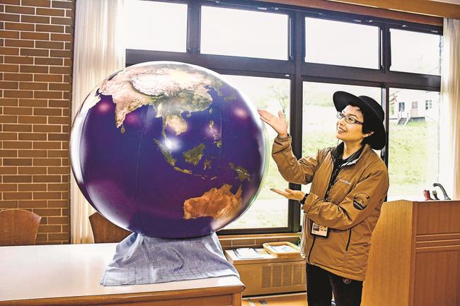 町営スキー場の関連施設で地球の模型を示す光島宏美プロジェクトマネージャー＝鳥取県江府町御机
