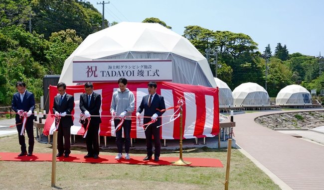 グランピング施設のドーム型テントをバックにテープカットする関係者＝島根県海士町福井