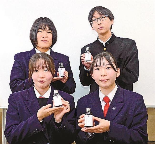 酒かすを活用したバスオイルのボトルを手にＰＲする出雲商業高校の生徒たち＝出雲市大津町、同校