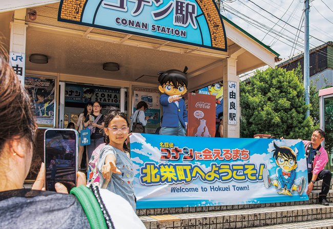 コナンの着ぐるみと記念撮影する観光客＝鳥取県北栄町由良宿、ＪＲ山陰線由良駅