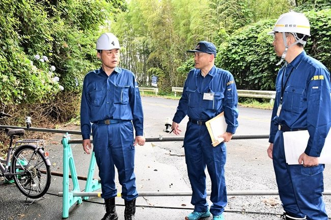 県道の崩落現場を視察し、県職員から説明を受ける丸山達也知事（左）＝出雲市大社町日御碕