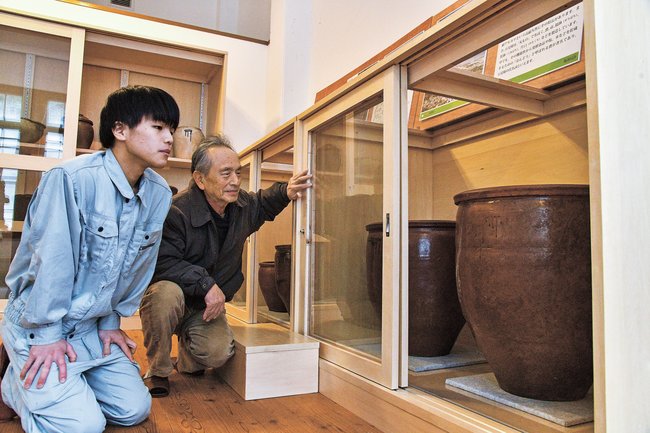遺物と木製棚を見つめるポリテクカレッジ島根の三代隆仁さん（左）と吉田茂会長＝江津市江津町、甍街道交流館