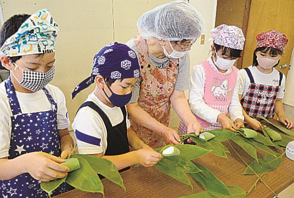 年配者（中央）に教わりながらササの葉でだんごを包む児童＝安来市広瀬町西比田