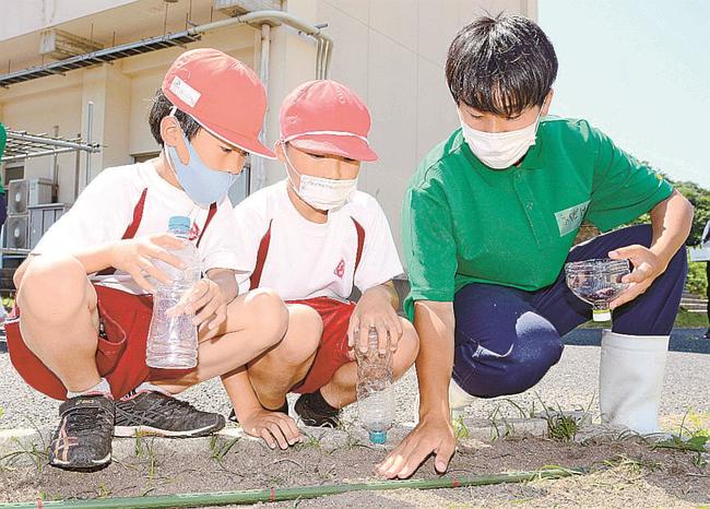 生徒（右）に種まきの方法を教わる児童＝大田市仁摩町仁万、仁摩小学校