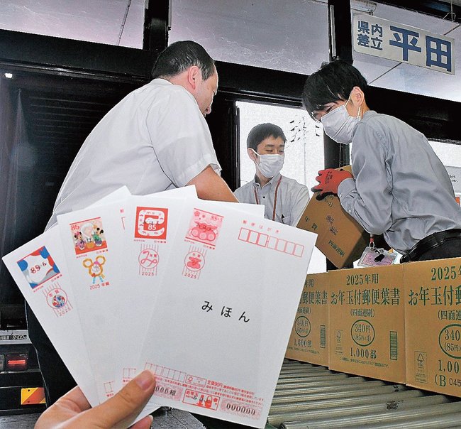 １０月の値上げで１枚８５円となった年賀はがきの見本と仕分けする郵便局員＝松江市東朝日町、松江中央郵便局
