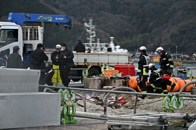 事故現場付近を調べる消防や警察、海上保安庁の関係者ら＝１０日午後５時半すぎ、境港市昭和町