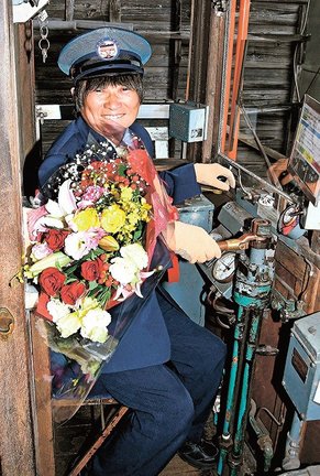 ２千回を達成し、運転席で花束を手にする増田義裕さん＝出雲市平田町、一畑電車雲州平田駅