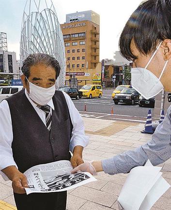 金メダル獲得を伝える号外を受け取る人＝米子市弥生町、ＪＲ米子駅前