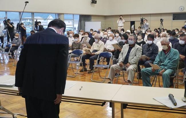 誤給付問題を巡り、山口県阿武町で開かれた住民向け説明会で謝罪する花田憲彦町長（手前）＝６月１日