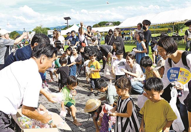 山陰中央新報社益田総局の移転を記念した餅まきで、喜んで餅を拾う参加者＝益田市高津町、島根県立万葉公園
