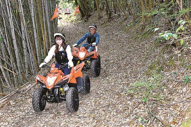 四輪バギーで山中のコースを走るスタッフ（手前）と草野剛之さん＝益田市美都町仙道