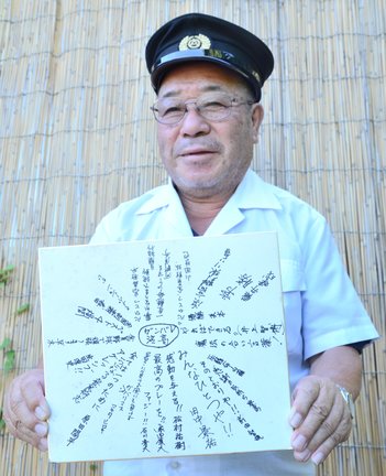 ２００４年夏の甲子園に出場した浜田高校野球部の寄せ書きを手にする岡田智さん＝浜田市三隅町井野